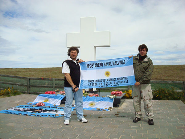 Imagen 4. Dos ex-combatientes que integraron el Apostadero (Claudio Guida y Juan Arias) en el cementerio argentino en Puerto Darwin en un viaje de regreso a las islas Malvinas en 2008. Portan una bandera con la leyenda 