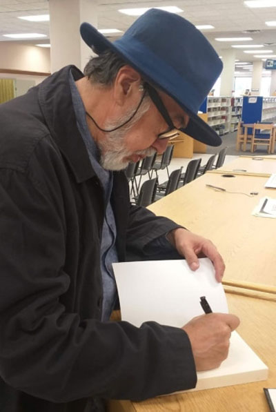 Ricardo Melgar Bao firma el libro de visitantes en la Biblioteca Central Carlos Montemayor, de la UACJ