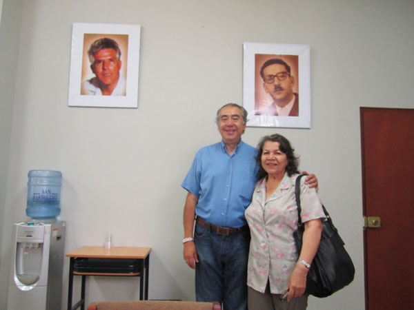 Ricardo Melgar y Angélica Aranguren con fondo de retratos de Alfredo Torero (izquierda) y Augusto Salazar Bondy (derecha), Sala de profesores de la UNMSM, Lima, 2014